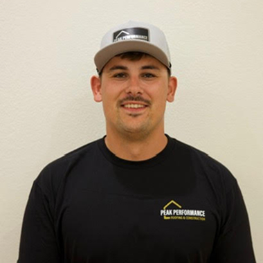 Young man in a black shirt and cap with Peak Performance logo.